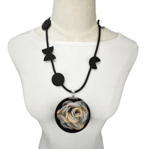 Black rubber rose pendant gothic necklace displayed on white mannequin torso, front view showing two-tone beige and gray fabric flower with geometric black rubber cord accents