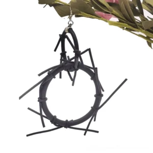 Single black spike hoop earring displayed flat against green foliage background, gothic punk style with protruding silicone spikes