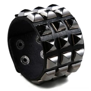 Black studded leather wide cuff bracelet with silver pyramid studs and snap button closure, showing geometric grid stud arrangement, gothic punk rock jewelry for women and men