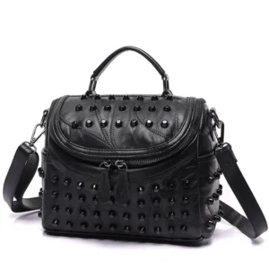 Black studded sheepskin leather crossbody messenger bag with dual front zippers and removable shoulder strap, front three-quarter view showing gothic aesthetic details