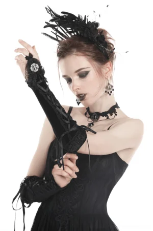 Black velvet fingerless gloves with cross lace-up design and ruffle cuff details, worn by female model in three-quarter view showcasing gothic style