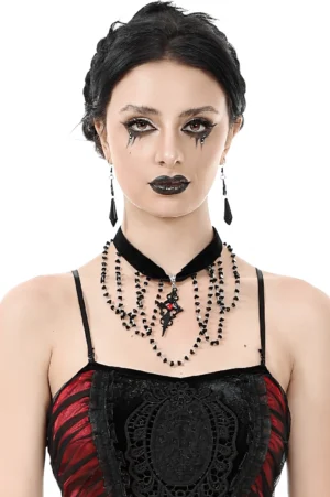 Black velvet gothic choker with beaded cross pendant worn by goth model, front portrait view with dramatic makeup and dark aesthetic