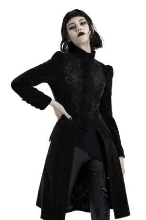 Black velvet gothic trench coat with stand collar and front floral embroidery, worn by model at three-quarter angle