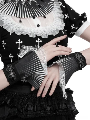 Female model wearing black and white lace fingerless gloves with pleated flare and metal tassel decor, paired with gothic cross print outfit, upper body fashion display
