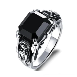 Black zircon gothic ring with winged skull motifs and square black gemstone, three-quarter front view showcasing carved stainless steel frame