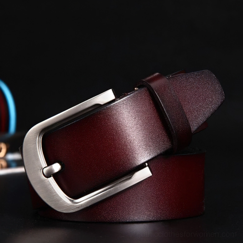 Wine red glossy cowskin gothic belt with silver metal buckle on dark background, side front profile view