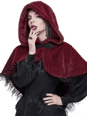 Wine red hooded gothic cape with feather fringe and fur pompon tail, front left close-up view on female model