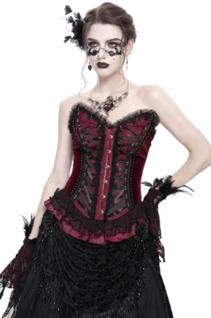 Burgundy gothic corset with black lace trim worn by model with gothic makeup and floral headpiece, front three-quarter view showing satin ribbon lacing and beaded chain details