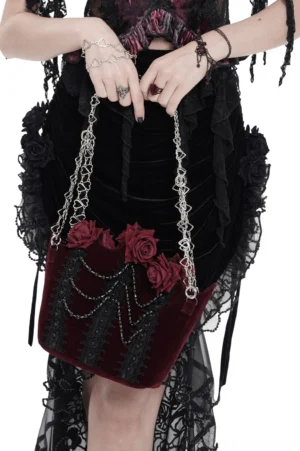 Burgundy gothic rose handbag side view worn by model in black lace gothic outfit, showing velvet texture and draped bead chains