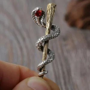 Cobra wand pendant held in hand showing coiled scaled serpent with red gem accent
