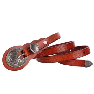Cognac brown leather belt with ornamental carved silver buckle, side profile showing embossed pattern, gothic alternative fashion