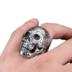 Ornate sugar skull punk ring worn on adult male hand showing three-quarter side view with intricate floral engraving patterns and polished finish
