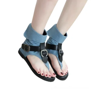 Woman wearing denim blue gladiator sandals with dual adjustable buckles and folded ankle straps, front low-angle model shot