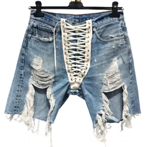 High-waist distressed denim shorts with white lace-up front closure displayed on hanger, flat lay view showing detail