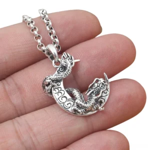 Dragon moon sterling silver pendant held in hand showing 3D carved detail, scale texture and dimensional relief carving, close-up finger reference for size