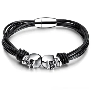Dual skull black gothic bracelet flat lay top view showing stainless steel charms and leather cord design
