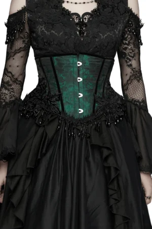 Emerald green jacquard gothic underbust corset with black beaded tassel trim, modeled on female in front three-quarter view wearing complete outfit with black mesh sleeves