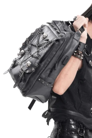 Side view of black punk gothic backpack held by model, displaying metal skull decorations and chain hardware details