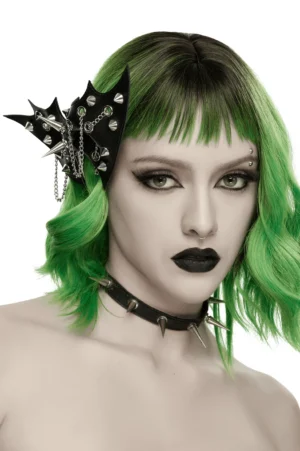 Close-up frontal view of gothic bat wing hair clip with metal rivets and dangling chains