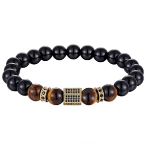 Gold tone cubic zirconia charm on black onyx and tiger eye beaded bracelet, gothic jewelry design, top down view