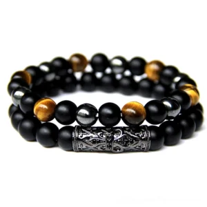 Black gothic beaded bracelet with tiger eye and onyx stones, metal engraved charm accent, flat lay overhead view