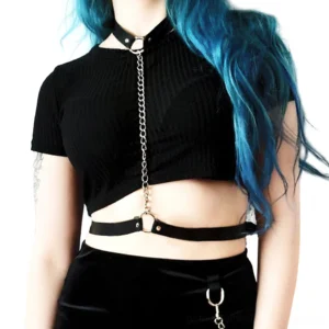 Blue-haired model wearing black gothic chain body harness over casual outfit, front styling view with metal O-ring details