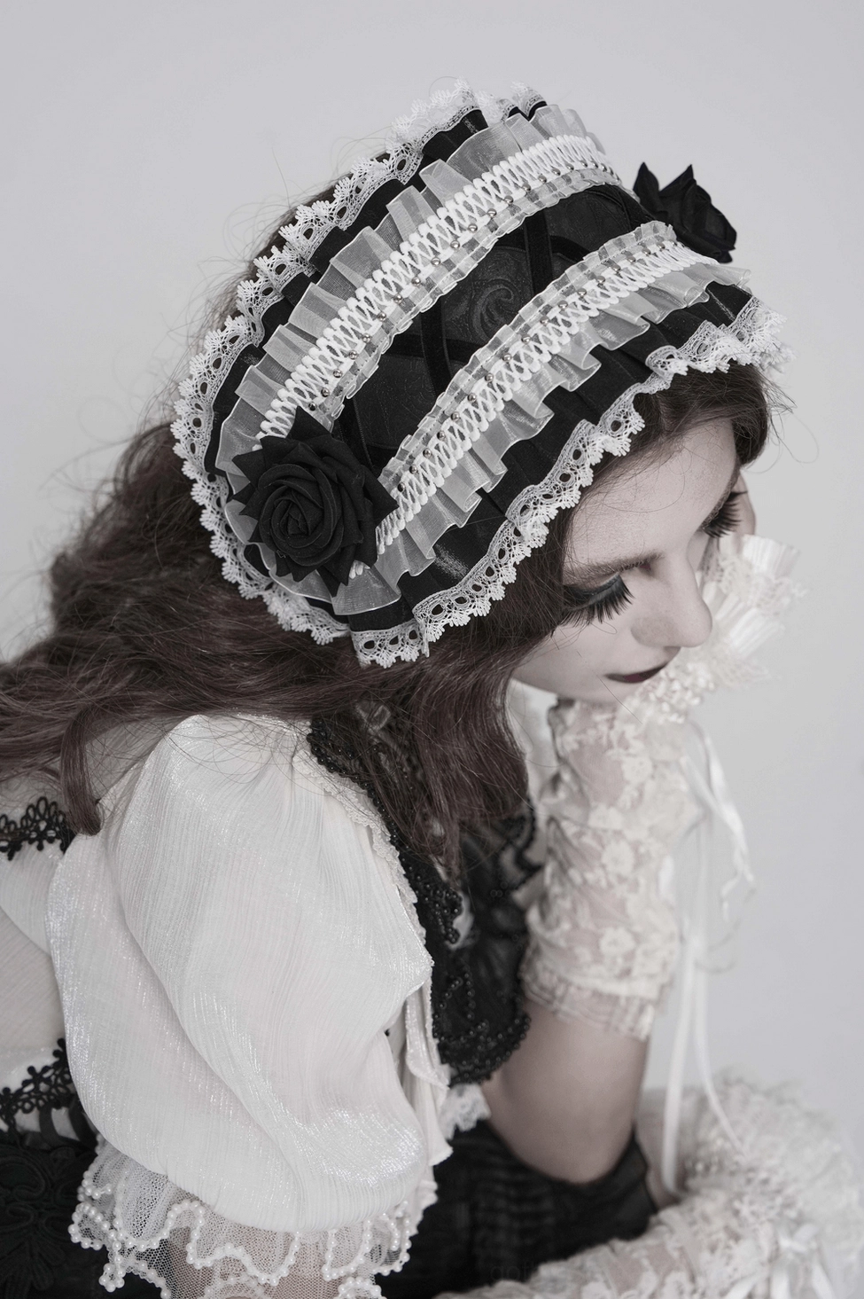 Detailed view of gothic lolita bonnet emphasizing black rose ornament and delicate lace trim work
