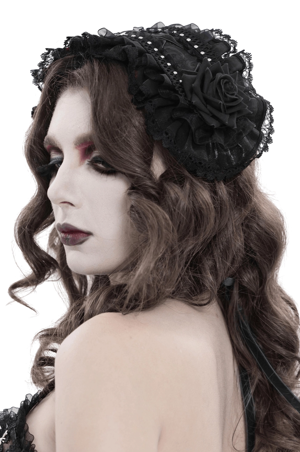 Black gothic lace bonnet with rose details shown on female model, left profile side view displaying layered ruffles and ribbon tie straps