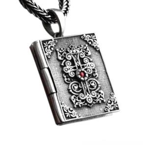 Gothic sterling silver book locket pendant with ornamental cross and red gemstone, three-quarter top view