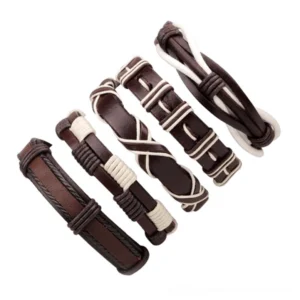 Five distinct gothic leather bracelets with white decorative accents arranged in flat lay, showing variety of designs and textures in woven rope chain style