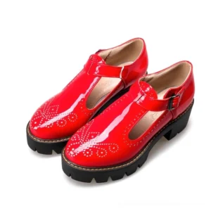 Deep red patent leather T-strap brogue platform flats with decorative perforations, three-quarter side angle showcasing gothic elegance