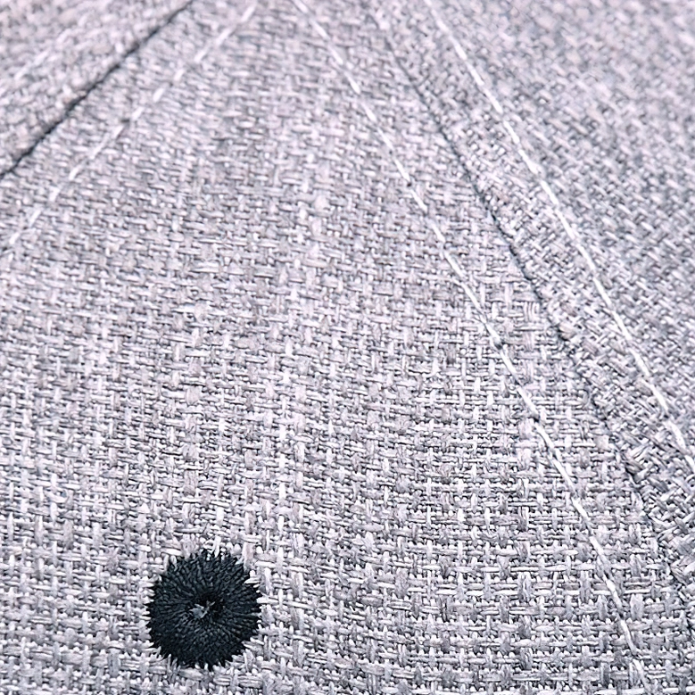 Macro view of gothic cap fabric texture showing woven heather weave and embroidered eyelet detail