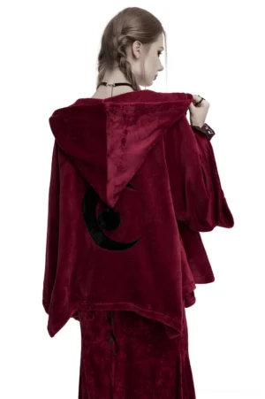 Black crescent moon embroidery detail on back of burgundy velvet gothic cape, worn by female model in studio setting