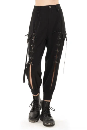 Black gothic cargo jogger pants with skull lace-up straps front view on female model wearing black pants with hollow-out side details and tapered hem