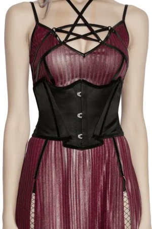 Black satin gothic underbust corset with bat wing design and lace-up back, styled with burgundy slip dress on model - front view
