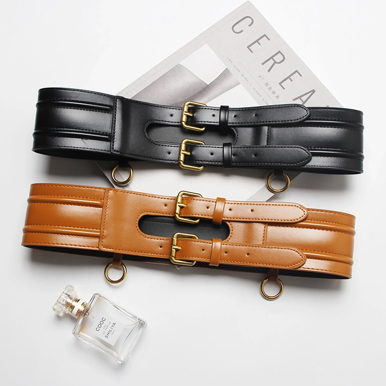 Two wide gothic corset belts - black and tan leather with gold buckles flat lay