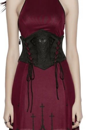 Black gothic waist corset belt with moth pendant and church embroidery worn by female model, front view with burgundy dress