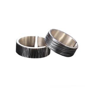 Pair of gothic sterling silver couple rings with distinct textured finishes, flat lay close-up showing open adjustable band design