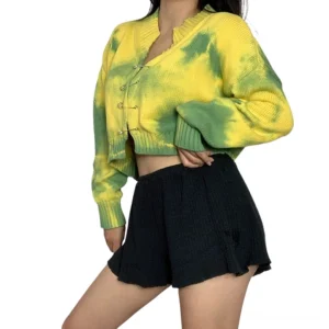 Yellow-green tie-dye gothic cropped cardigan with safety pin closures, front three-quarter view on model