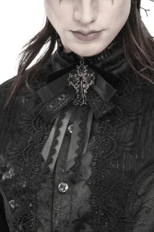 Black gothic cross bow brooch with ornate pendant displayed on embossed dark lace shirt with sheer ribbon accents