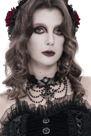 Black rose lace gothic cross choker necklace modeled on goth woman with red flower hair accessory, front view showcasing beaded chain layers and ornate cross pendant