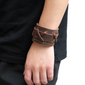 Gothic cross-laced leather bracelet worn on male arm, tan brown genuine leather with distressed vintage texture, side close-up daily wear view