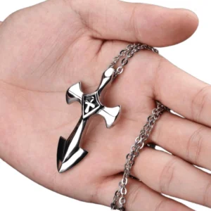 Hand holding gothic cross pendant necklace showing linked chain detail and silver metal construction, overhead close-up perspective