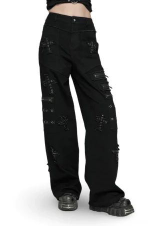 Black cross-patch gothic denim pants with metal zippers, front three-quarter view on female model, showing structural details and punk aesthetic