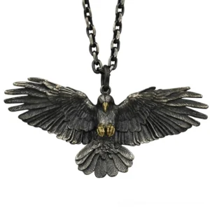Blackened silver crow pendant necklace front view with spread wings and golden talons, vintage gothic jewelry on flat display