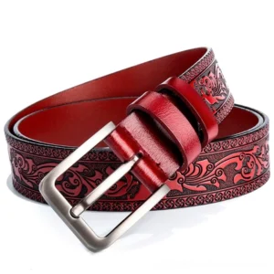 Wine red embossed gothic leather belt with ornate floral carving and silver pin buckle, top oblique view showing texture detail