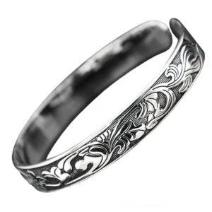 Vintage open cuff bracelet side angle showing carved vine floral motifs and antiqued silver metallic finish