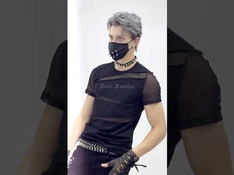 Gothic face mask styled with matching studded gloves and choker worn by male model in dark studio lighting, demonstrating complete alternative fashion ensemble coordination