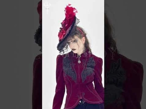 Three-quarter front view of gothic fascinator worn by dark aesthetic model with embroidered velvet formal coat against dark studio background