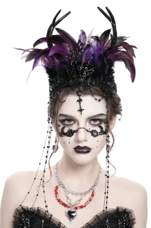 Female model wearing black-purple feathered gothic crown with cross face chains and theatrical gothic makeup, front close-up studio view